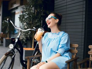 timber-lofts-woman-sitting-on-bench-outside-with-bicycle-and-beverage